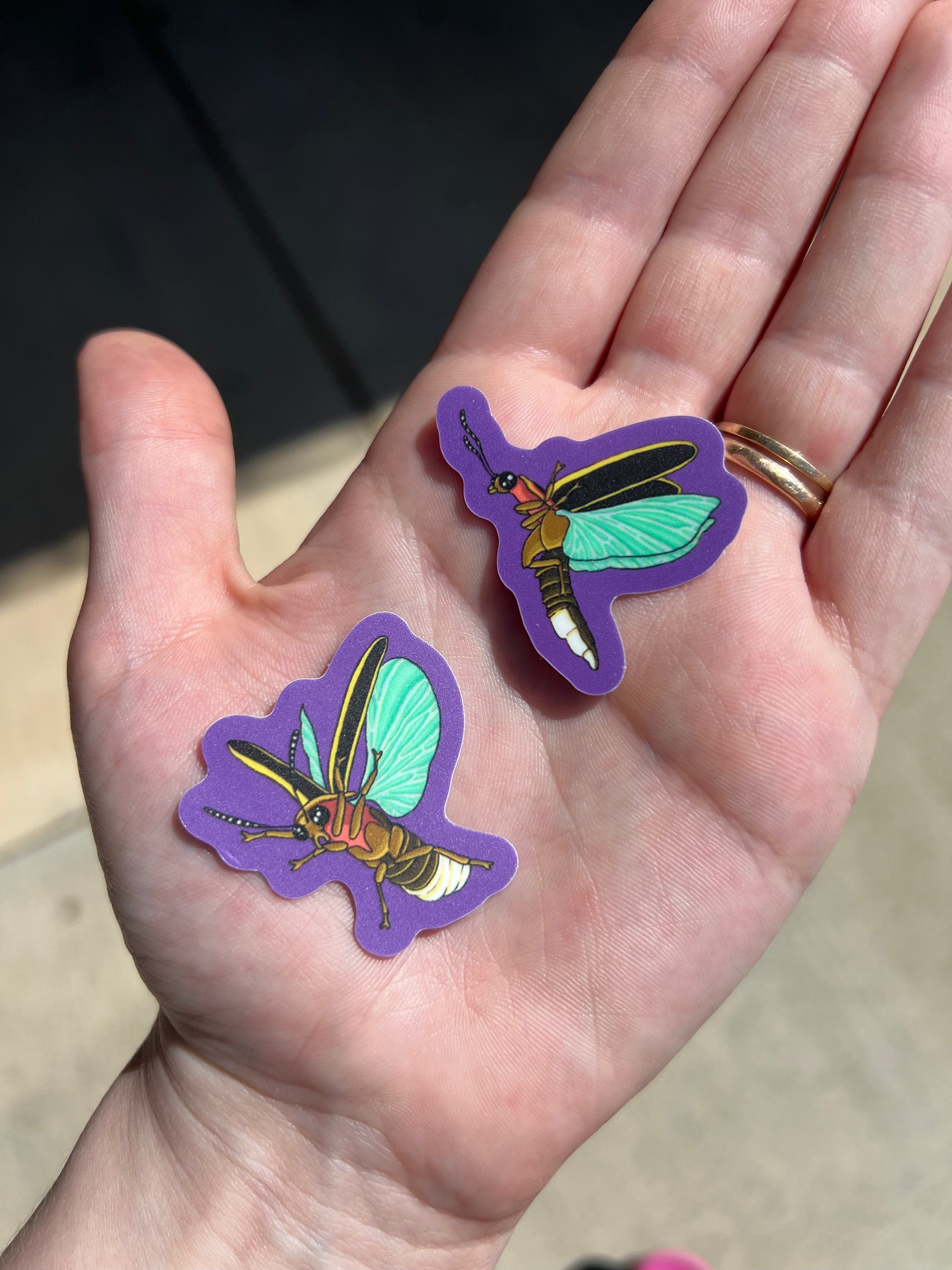 two firefly stickers made of glow in the dark vinyl, charging in the sun.